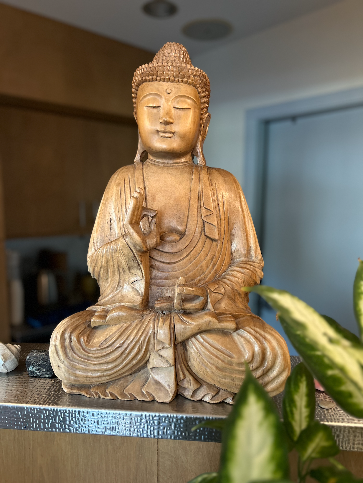 This wooden Buddha has kept our deskers company for many years now. He came to us from a Buddhist shop in South Miami Beach after we renovated the studio in 2006. This Buddha is shown performing vitarka mudra. The right hand makes a circle out of the thumb and forefinger, a symbol of the great wheel of the Buddha’s teaching that rolls onward through time and communities.
Click on this image to see a collection of mudras in Buddhist art!